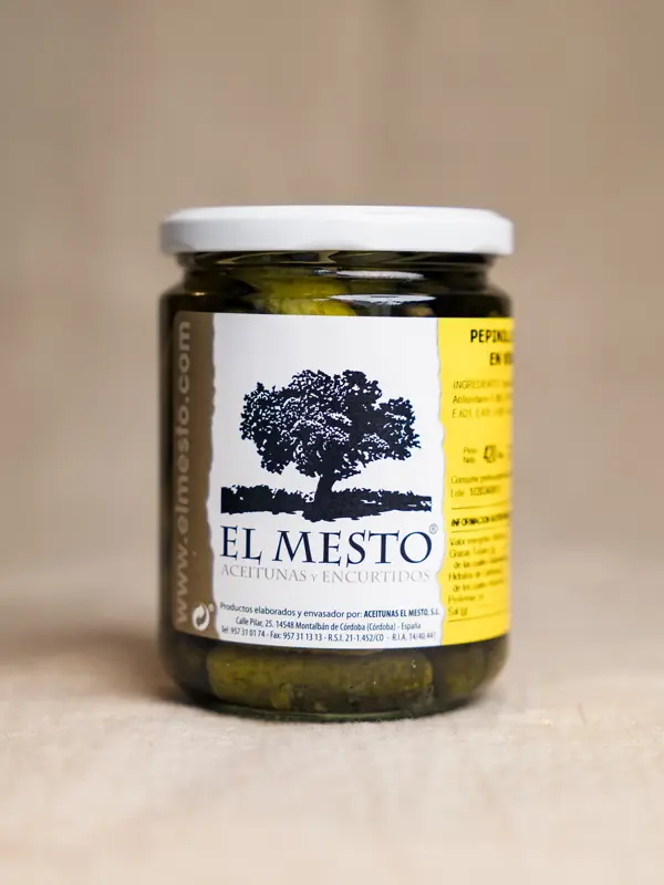 Glass med El Mesto Pepinillos Extra en Vinagre – små, sprø agurker syltet i eddik, presentert i en klar glasskrukke med etikett, perfekt som spansk delikatesse. Pettersen&Co