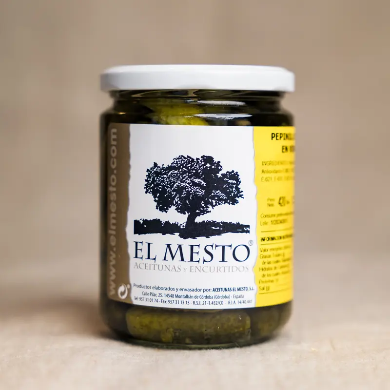 Glass med El Mesto Pepinillos Extra en Vinagre – små, sprø agurker syltet i eddik, presentert i en klar glasskrukke med etikett, perfekt som spansk delikatesse. Pettersen&Co