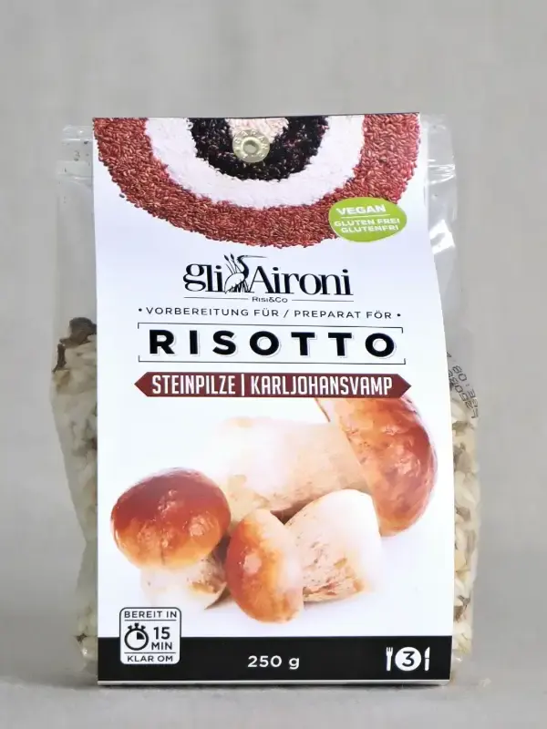 Pakke med Gli Aironi risottomiks med steinsopp 250g, plassert på kjøkkenbenk med risottoskål, parmesan og hvitvin.