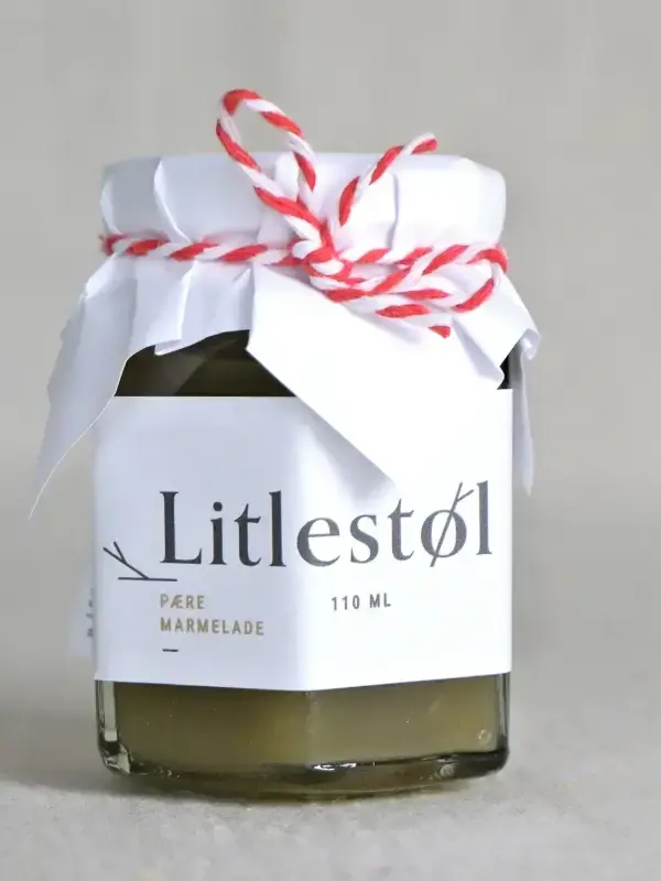 Glass med Litlestøl pæremarmelade 110ml, plassert på et trebord med ost, nøtter og ferskt brød.